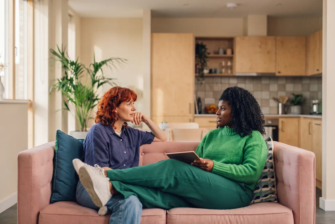 Two people talking through a plan on a sofa, one with a tablet